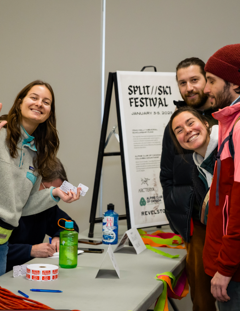 A group of people smiling at an informational booth for the Split/Skis Festival, with event posters and promotional materials on the table.