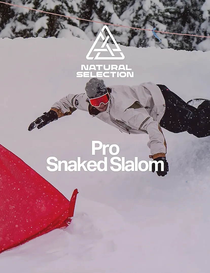 Snowboarder in mid-air during a slalom, wearing a white jacket and black pants with snow-covered trees in the background.