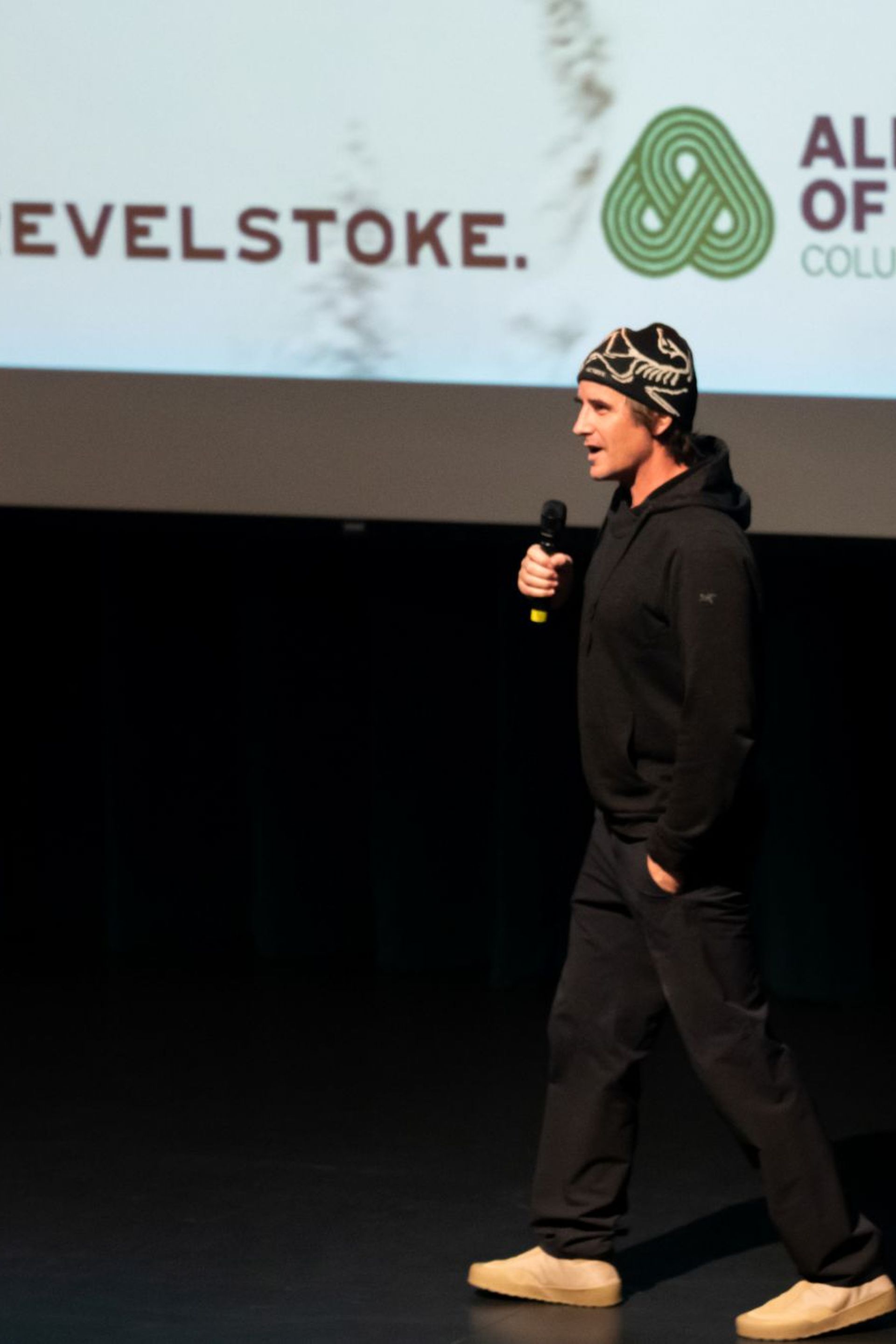 man speaking on stage at film night