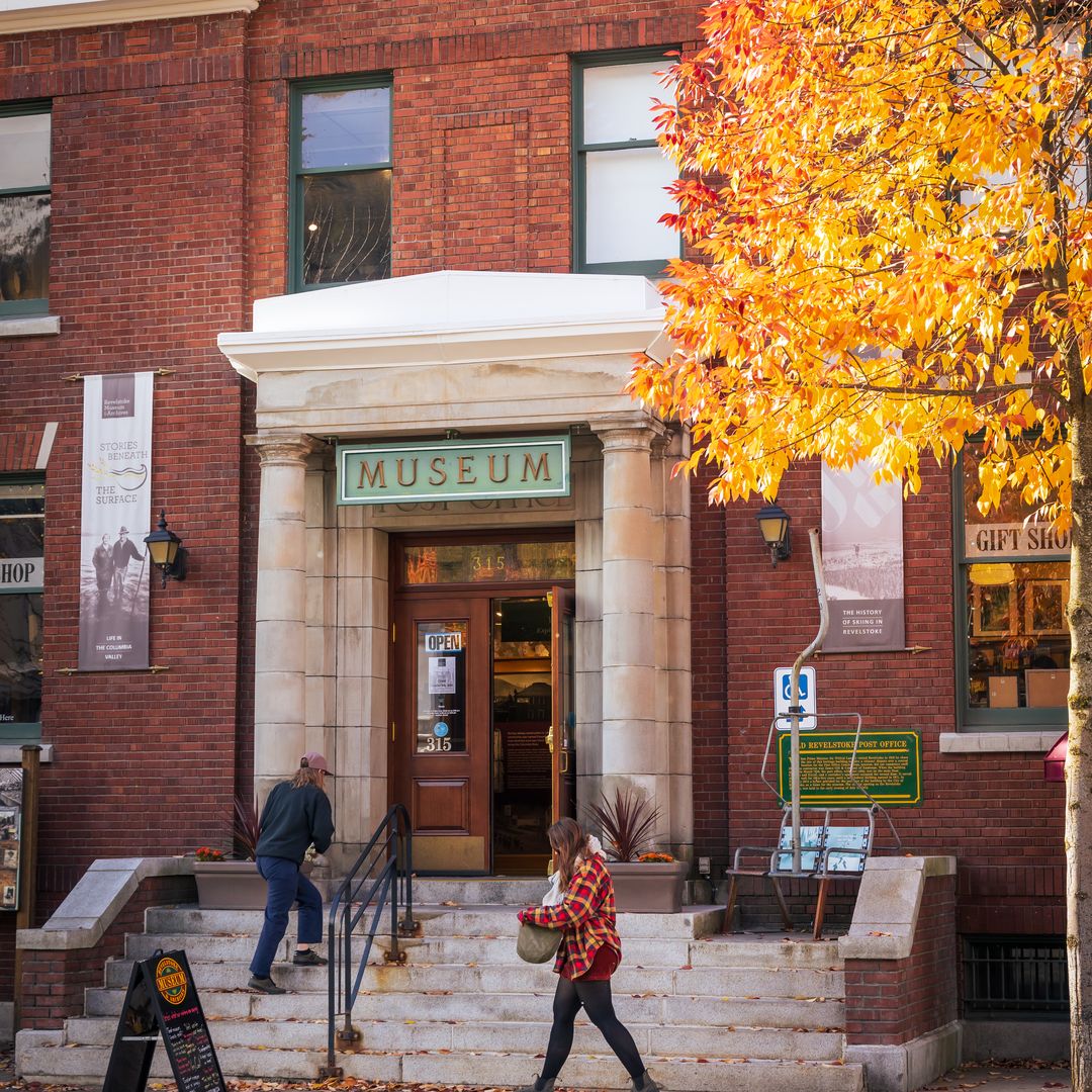 two girls walking into museum with maple leaves falling from nearby