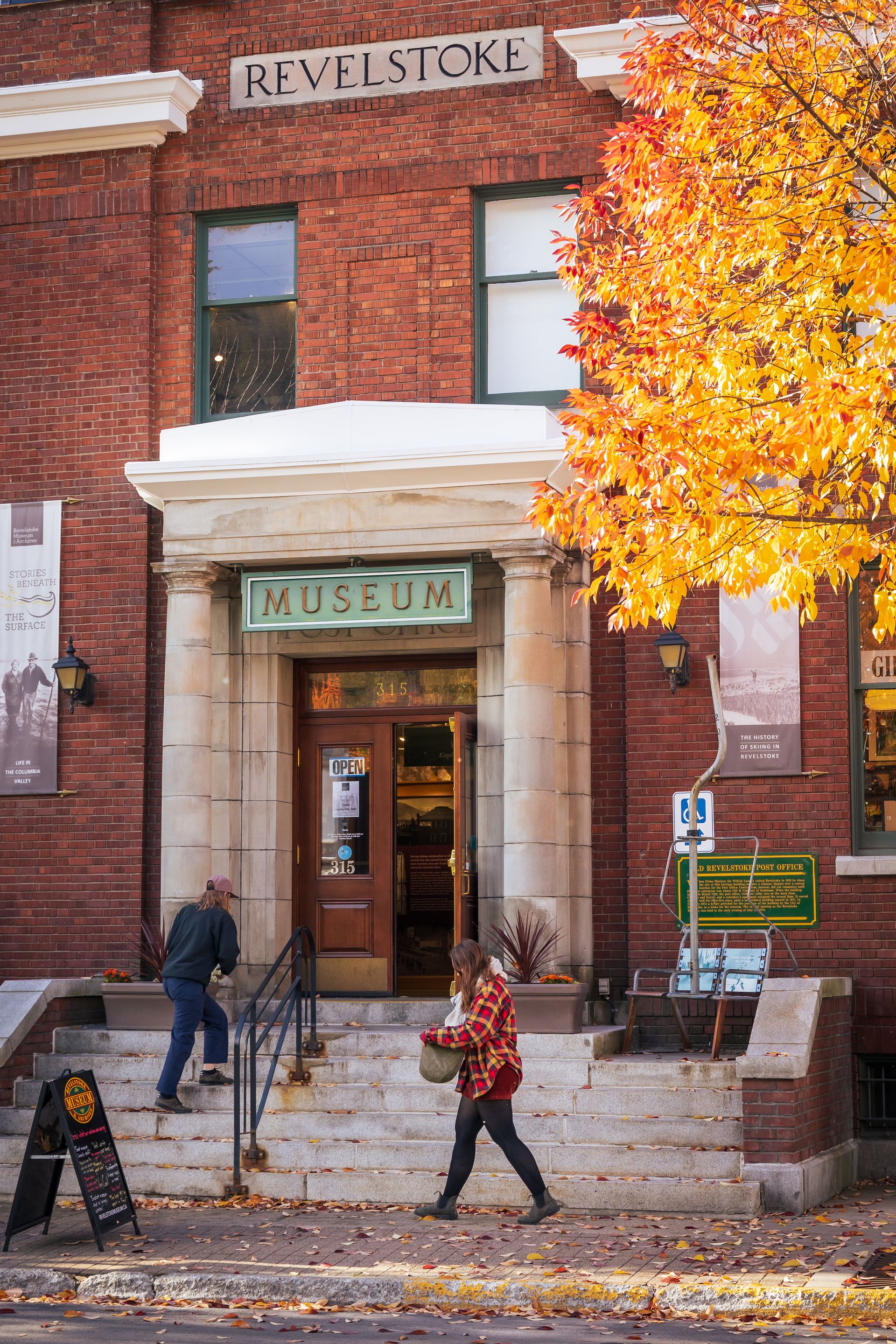 two girls walking into museum with maple leaves falling from nearby