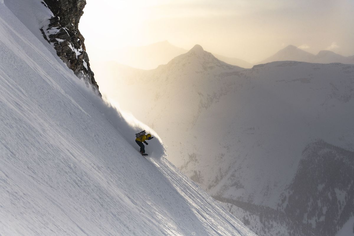 snowboarder spraying pow on steep terrain