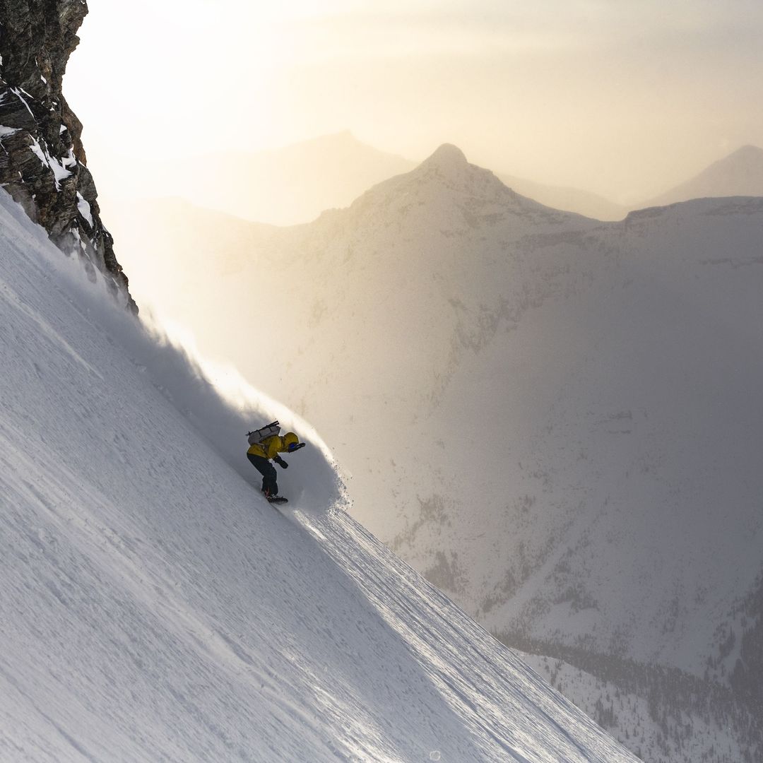 snowboarder spraying pow on steep terrain