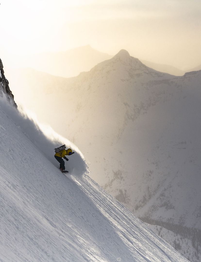 snowboarder spraying pow on steep terrain