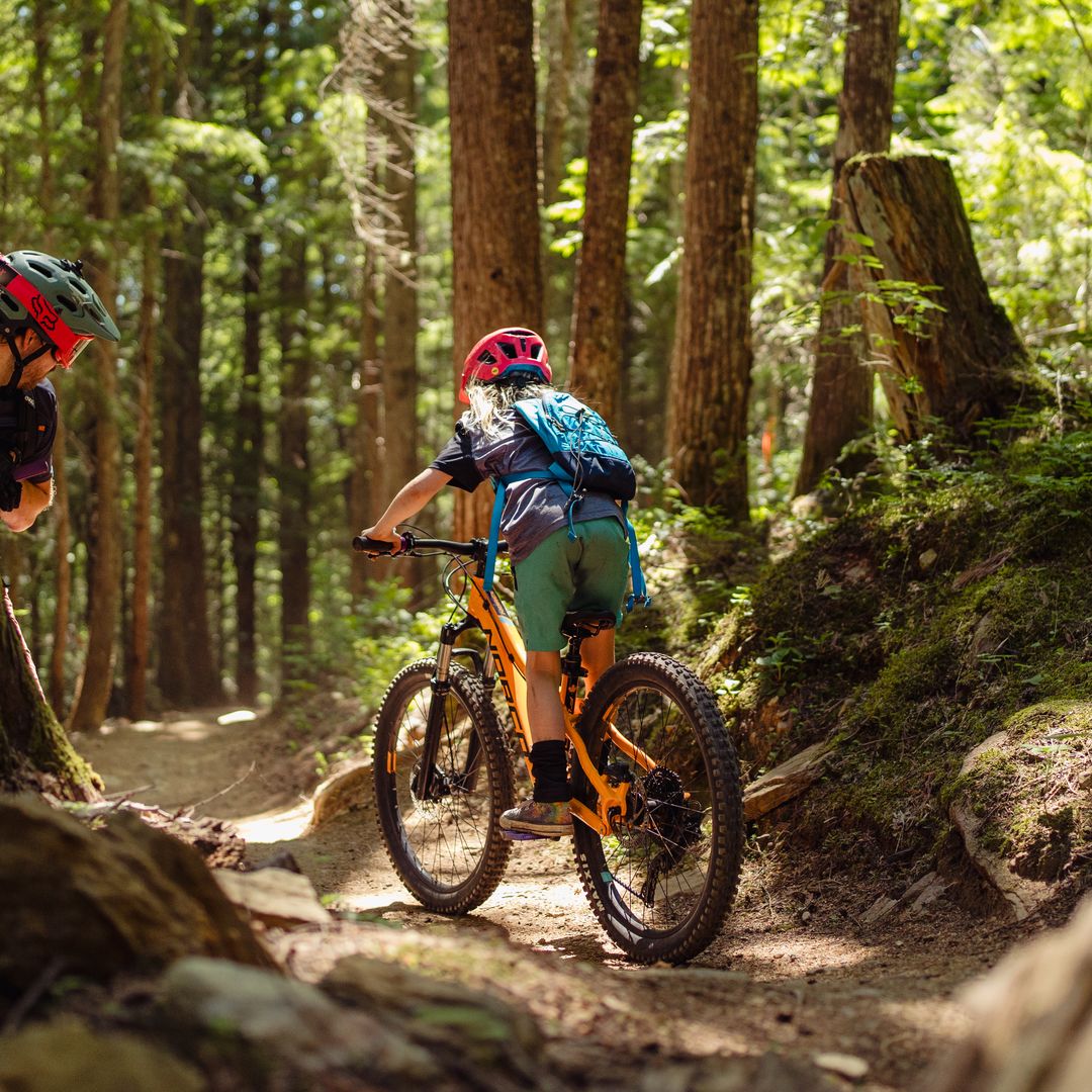 kid and dad mountain biking on forest trail