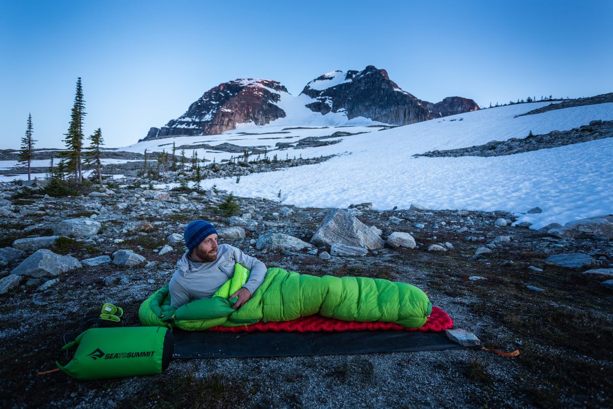 man in sleeping bag in alpine camping
