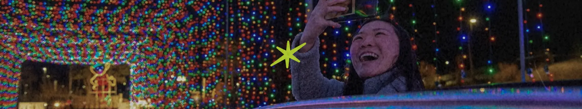 women filming light show in car drive thru christmas season holiday light show with kindling cannabis delivery cannabis store spark logo in neon