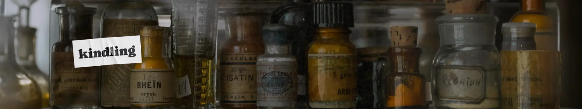 A collection of vintage apothecary bottles with faded labels displayed on a shelf, with the word "kindling" cannabis dispensary logo