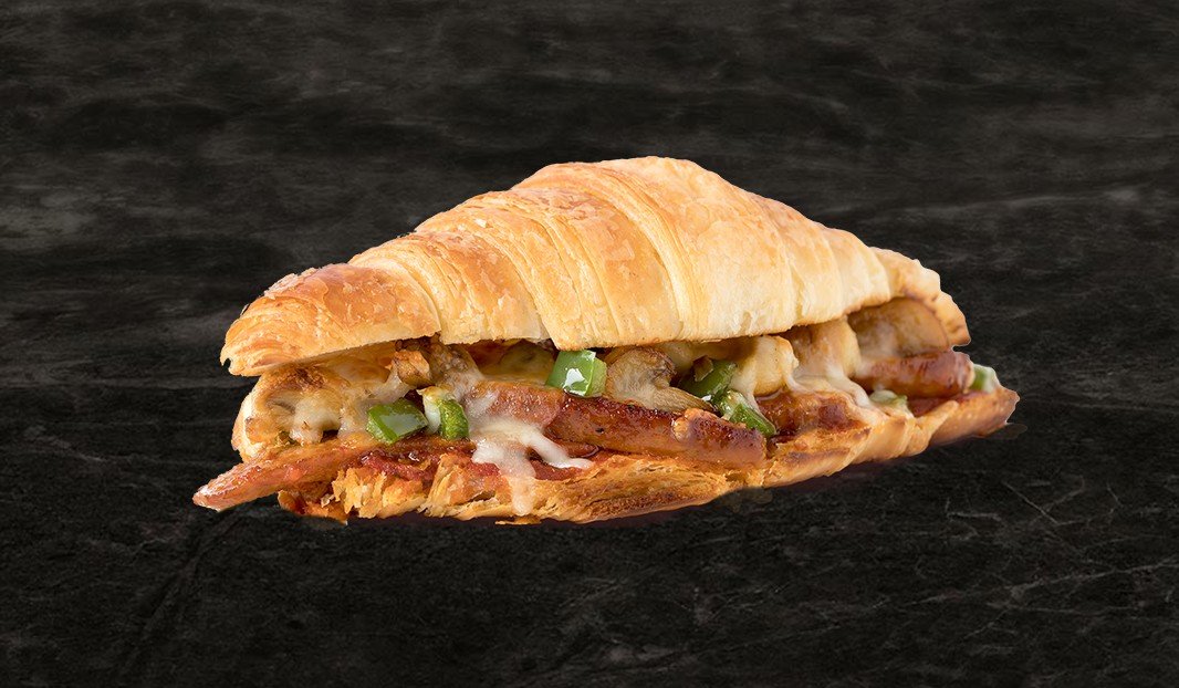 Croissant garni de viande grillée, fromage fondu et poivrons verts.