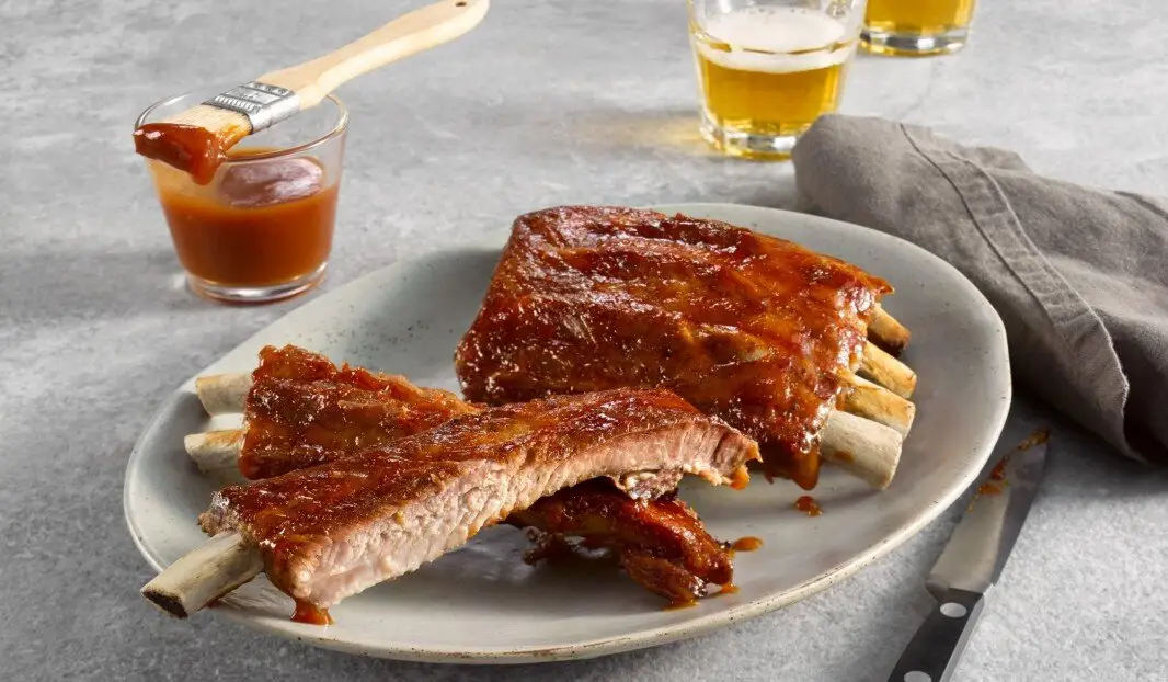 Côtes levées barbecue avec sauce et bière en arrière-plan