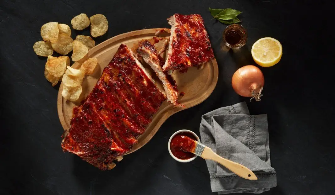 Côtes levées barbecue sur planche avec chips et sauce.