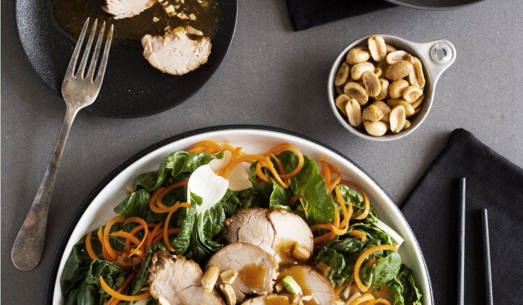 Assiette avec porc tranchée, légumes verts et carottes spiralées