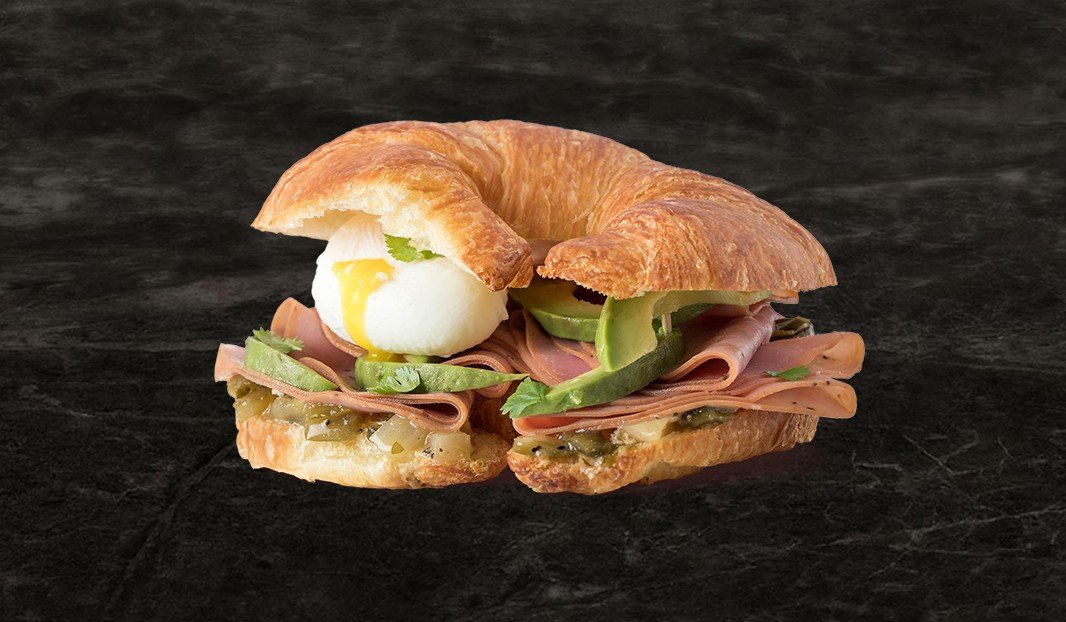 Croissant garni de jambon fumé, avocat, œuf poché et verdures.