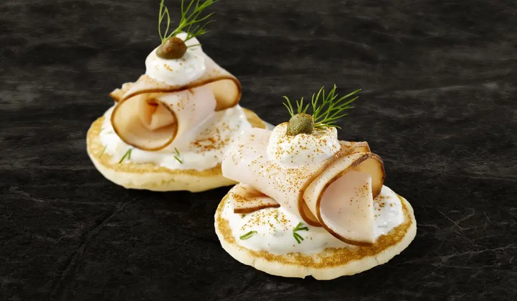 Blinis garnis de dinde, crème, câpre et aneth frais.