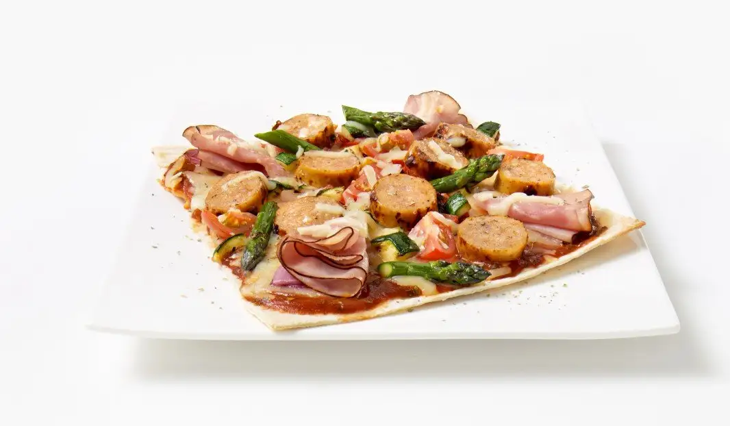 Pizza garnie de saucisse italienne, jambon fumé et légumes grillés