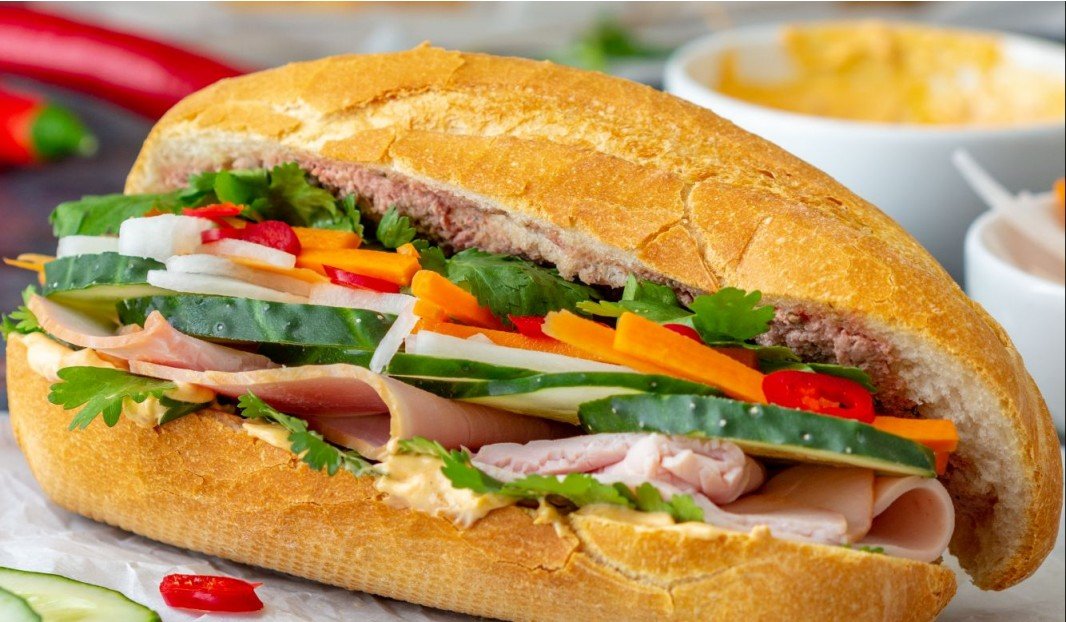 Sandwich avec baguette, concombres, légumes marinés, coriandre et jambon