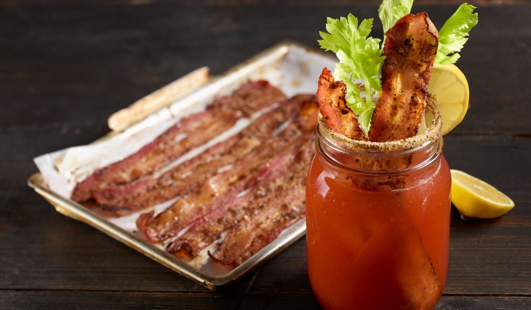 Verre de Bloody Ceasar garni de bacon épicé et céleri