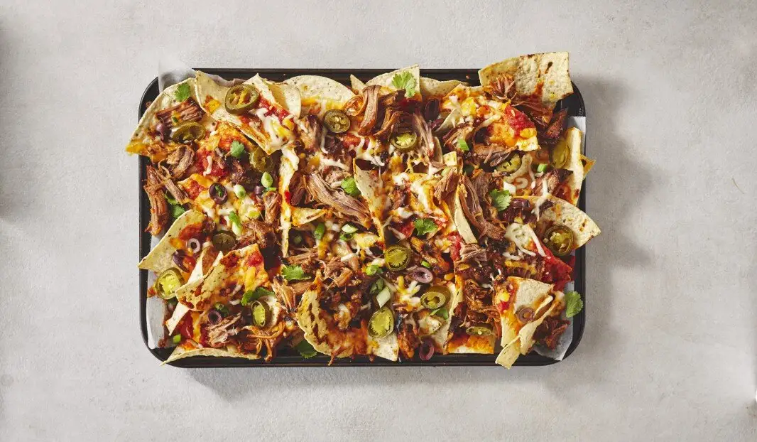 Plateau de nachos avec porf effiloché, fromage fondu et jalapeños.