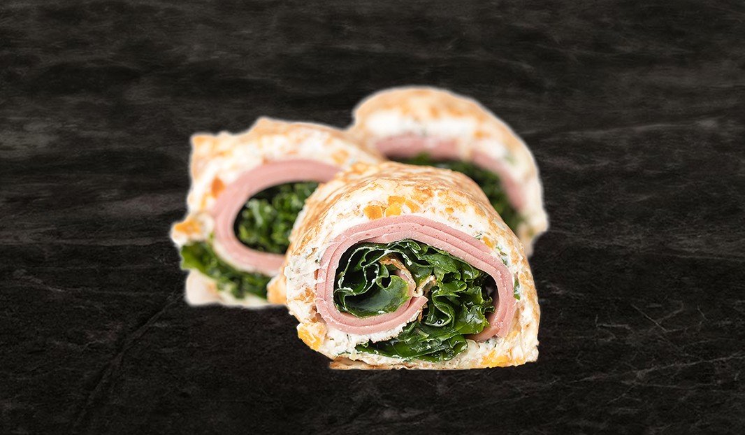 Wrap roulé au bologne, fromage et verdures, coupé en deux.