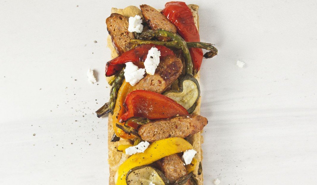 Tartelette feuilletée garnie de légumes rôtis, hummus et saucisse