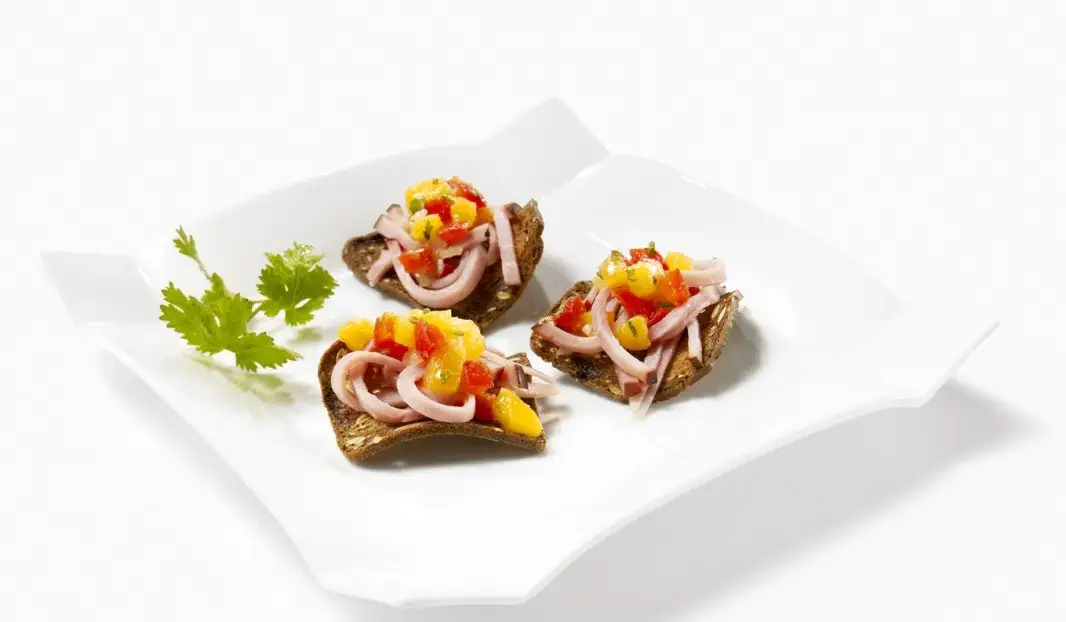 Canapés de jambon garnis de chutney de pêches sur craquelins.