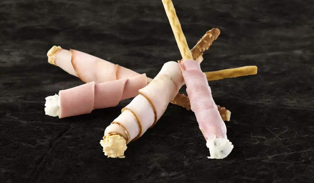Grissinis en croix, enrobés de charcuteries variées et fromage.