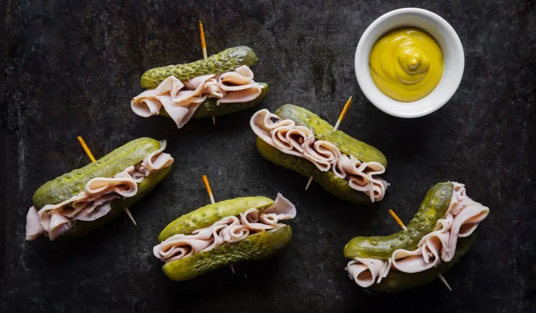 Cinq mini-sandwichs aux cornichons avec viande froide et moutarde.