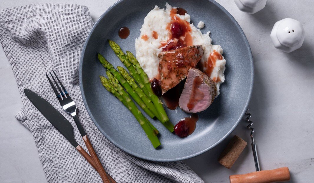 Assiette avec asperges, purée de pommes de terre, porc et sauce.
