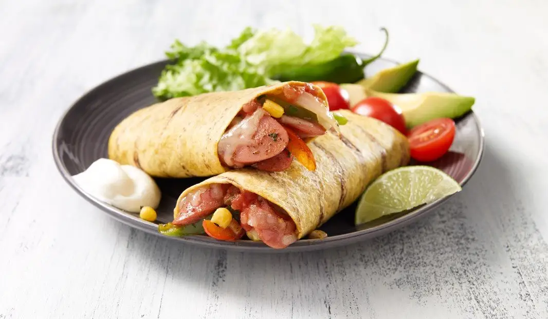 Tortilla grillée garnie de saucisses fumées et légumes colorés