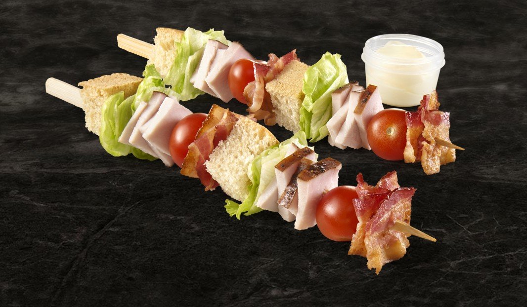 Brochettes de pain, viande, bacon, laitue et tomates avec sauce.
