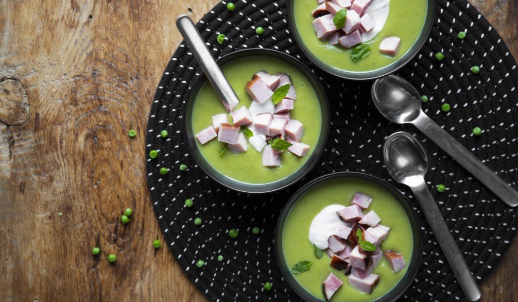 Trois bols de soupe aux pois verts avec crème fraîche et jambon Forêt-Noire.