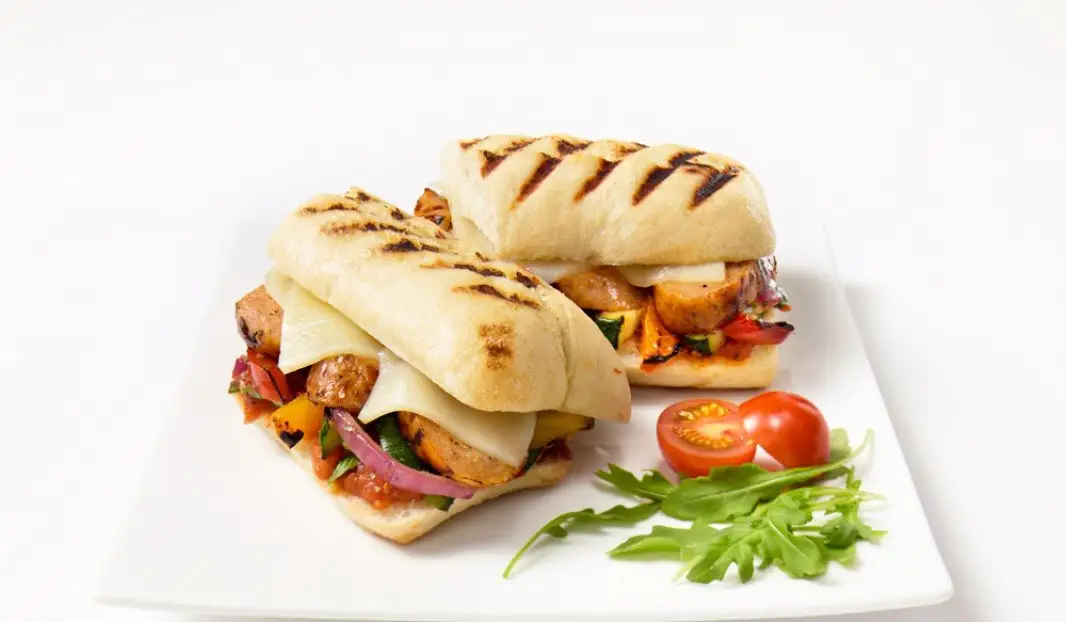 Panini grillé garni de saucisse italienne et légumes