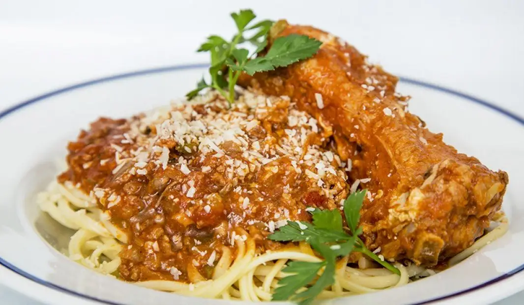 Assiette de spaghetti nappée de sauce aux côtes levées et parmesan