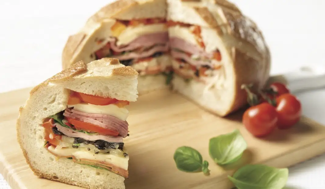 Sandwich muffuletta tranché avec viandes froides et légumes grillés