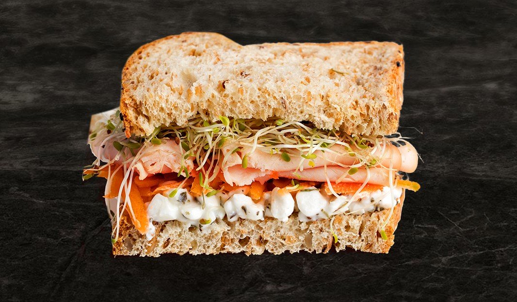 Sandwich à la dinde, carottes, germes et fromage cottage sur pain complet.