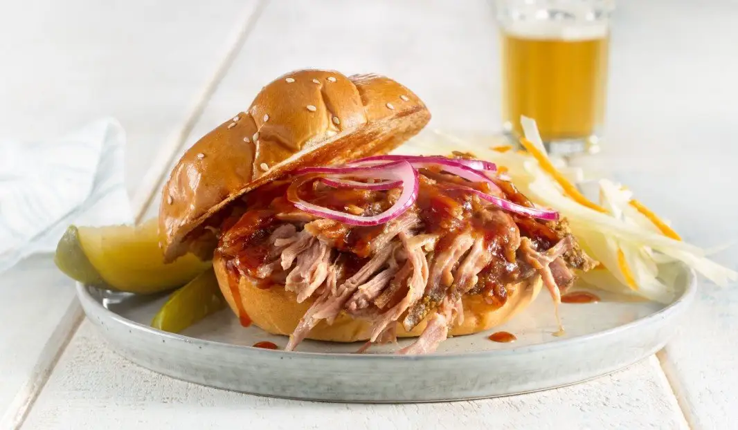 Sandwich de porc effiloché avec sauce barbecue, oignons rouges et coleslaw