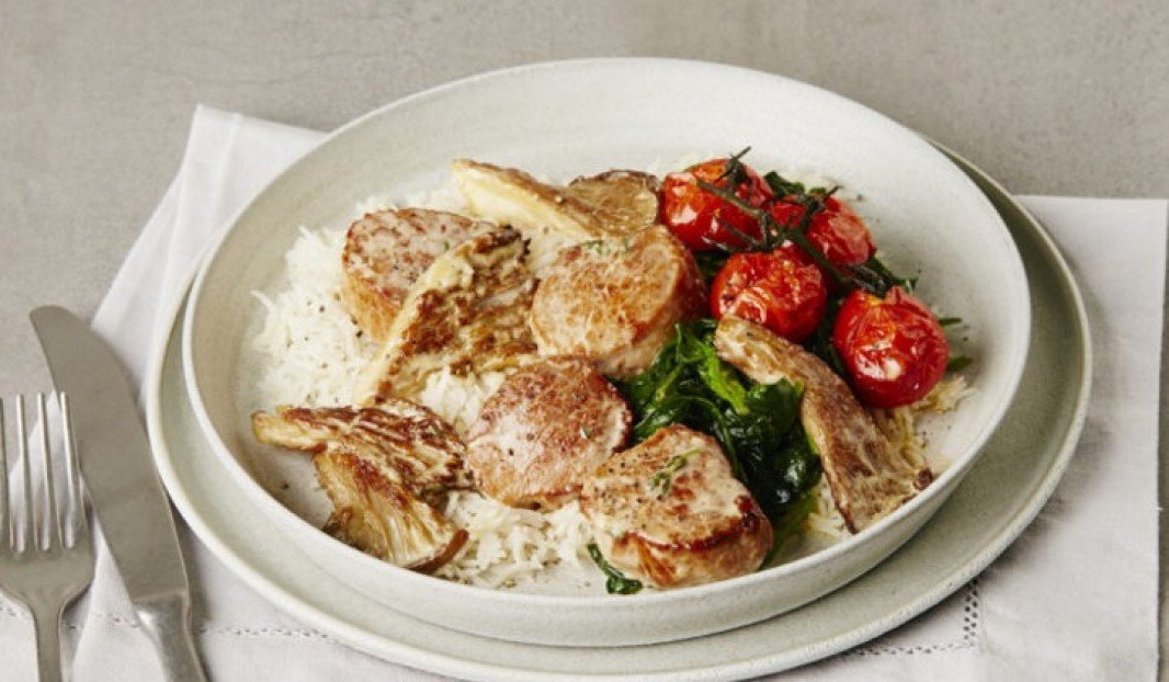 Assiette de prorc grillée avec tomates et épinards sur riz.