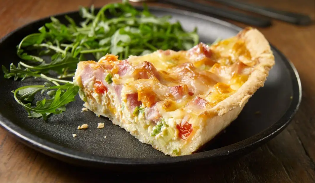 Quiche dorée garnie de patates douces, jambon et poivrons