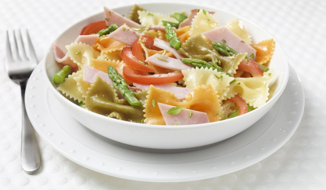 Assiette de pâtes colorées avec jambon et légumes sautés