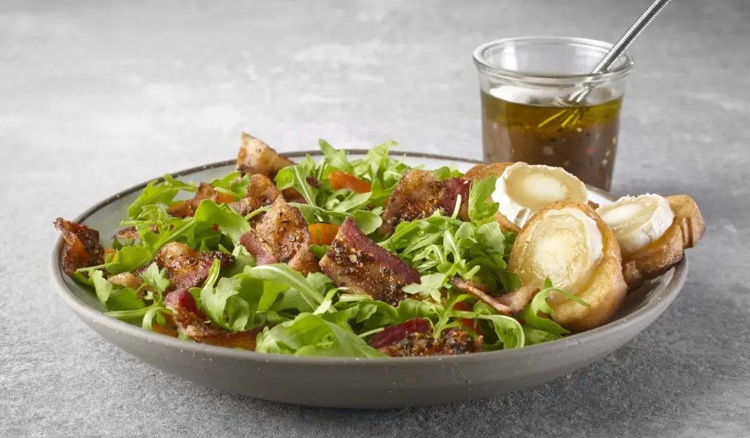 Salade de roquette garnie de bacon poivré et croûtons de chèvre