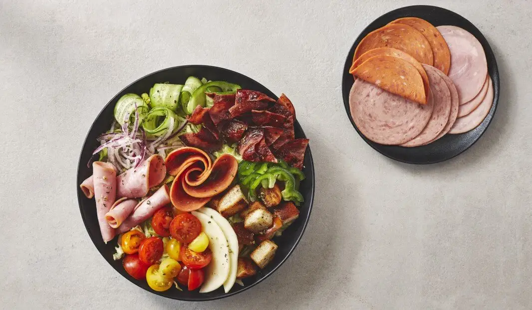 Assiette de charcuterie avec légumes, fromage et croûtons.