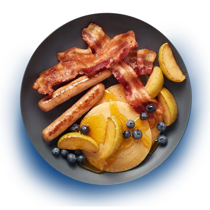 Assiette déjeuner avec saucisses, bacon, crêpes et fruits