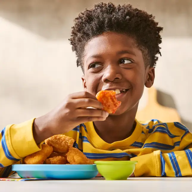 Un enfant qui mange une croquette
