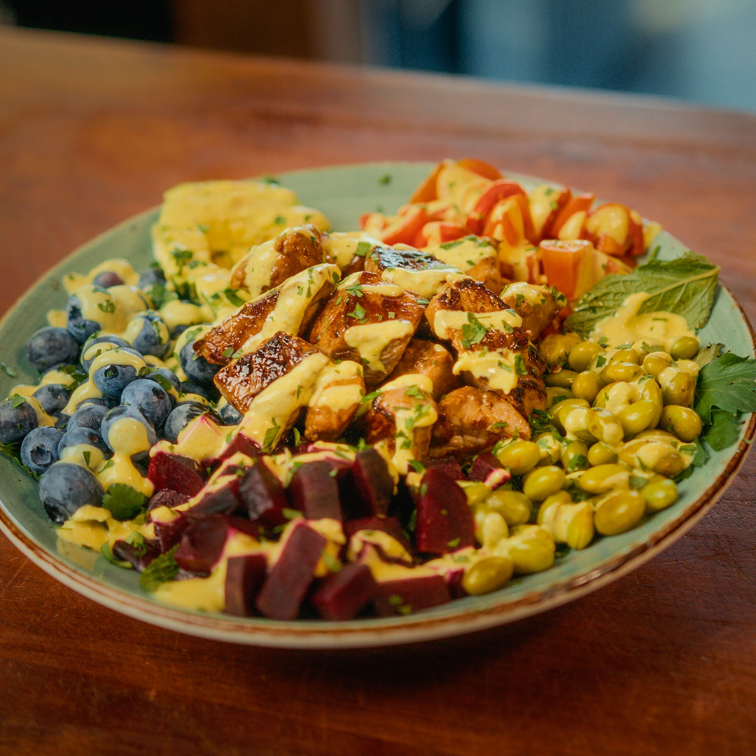 Bol de porc mariné miel et ail avec tomates, edamames, betteraves, bleuets et sauces