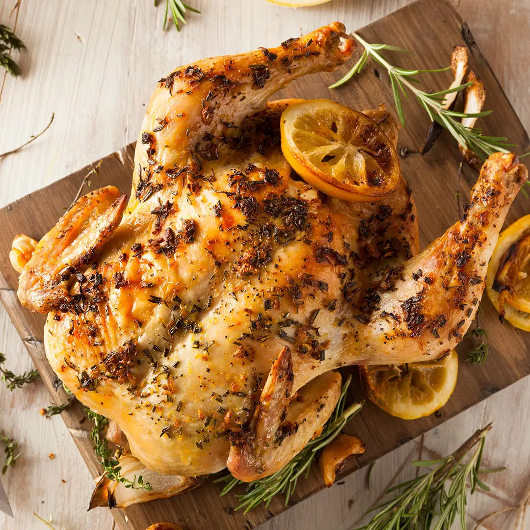 Poulet entier cuit et assaisonné sur une planche à couper
