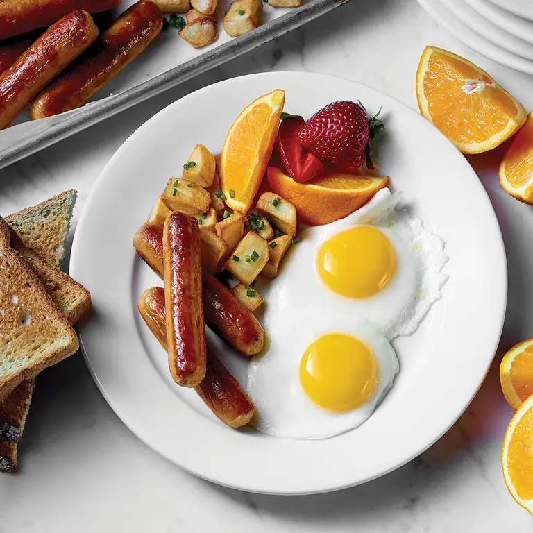 Assiette déjeuner avec oeufs, saucisses déjeuner, patates et fruits