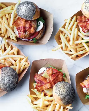 Burger avec boulette de viande, bacon, laitue, tomate, fromage sur pain au graines de pavot, avec des frites sur le côté