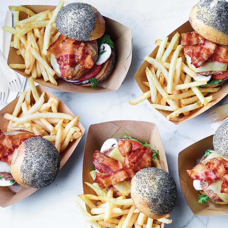 Burger avec boulette de viande, bacon, laitue, tomate, fromage sur pain au graines de pavot, avec des frites sur le côté