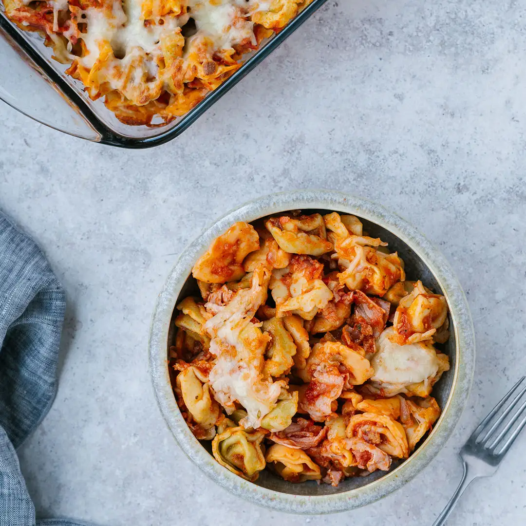 Bol de tortellinis gratinés au jambon fumé forêt noire sur un comptoir gris