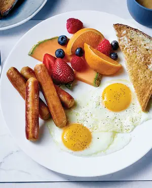 Assiette déjeuner avec oeufs, saucisses déjeuner, toast et fruit